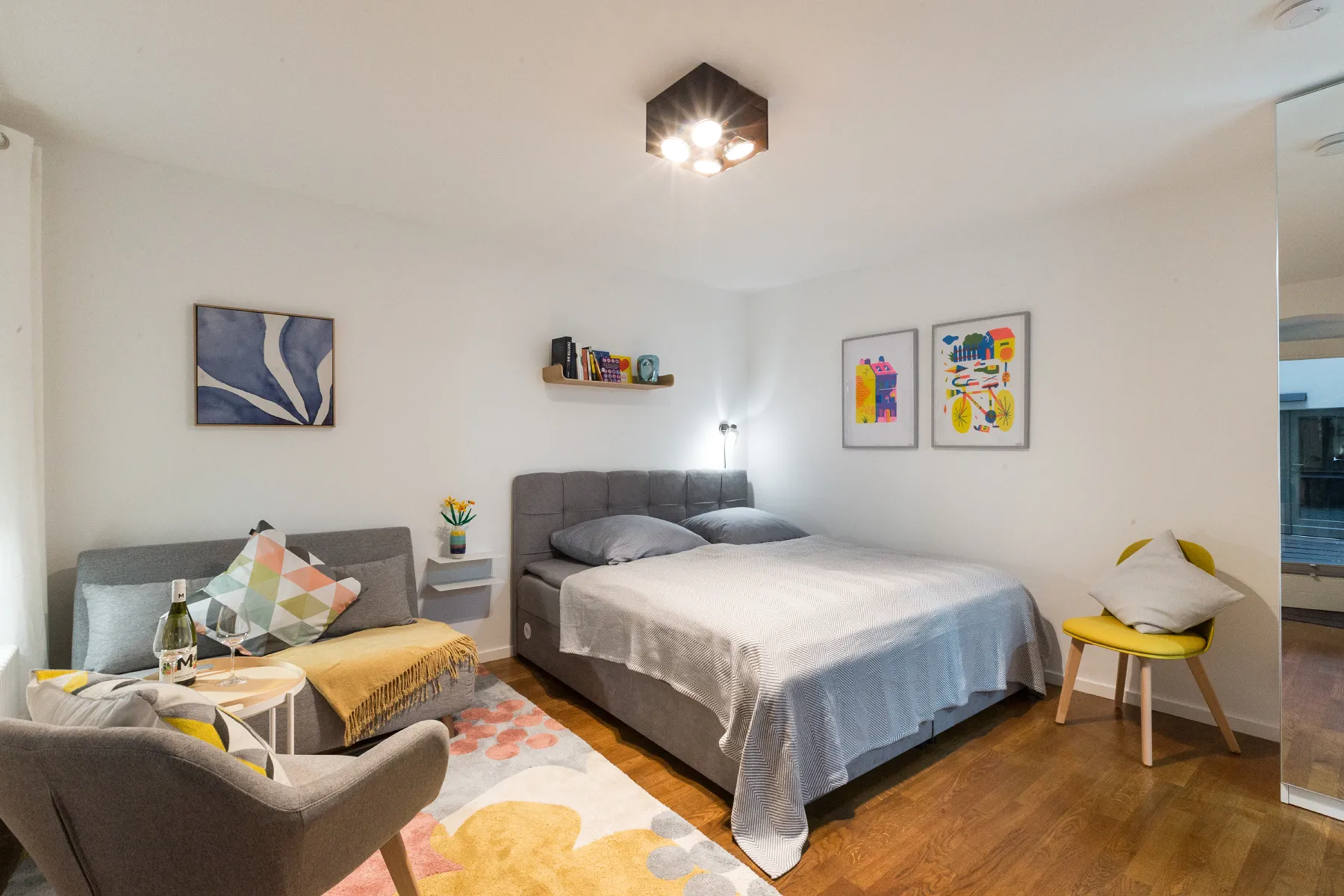 Heller Wohn- und Schlafbereich des J8 Studioapartments in Berlin-Mitte mit Doppelbett, kleinem Sofa und Sessel
