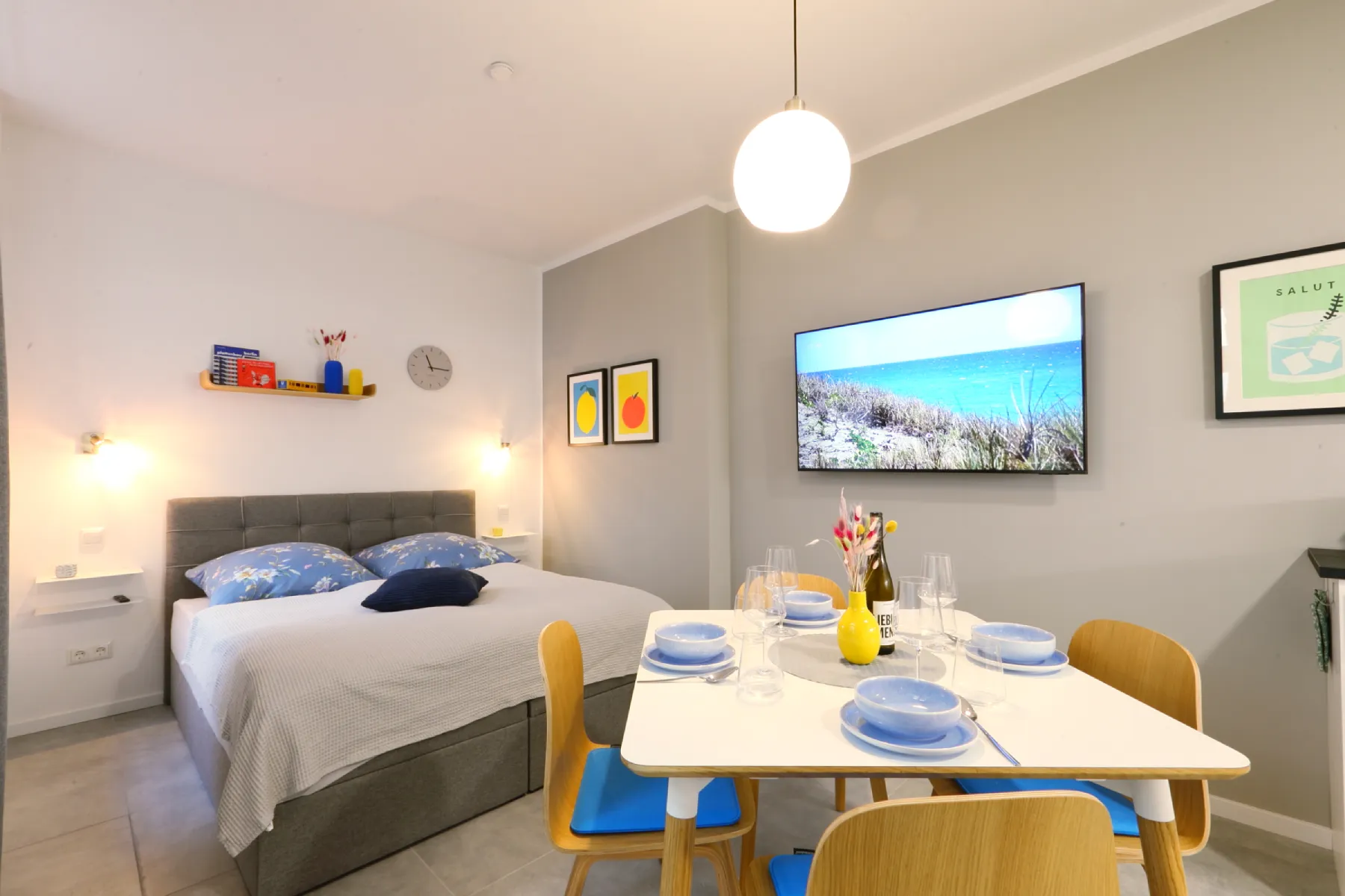 Offener Wohn- und Schlafbereich der K47 Wohnung in Berlin-Mitte mit Doppelbett, Esstisch und Wand-TV